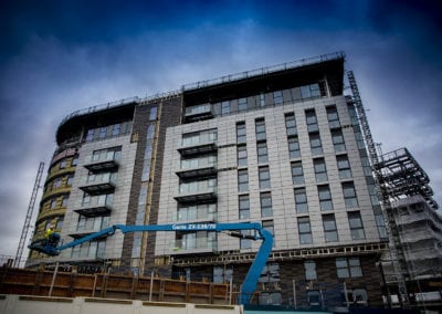 Modern high-rise building under construction with Genie ZX-135/70 boom lift.