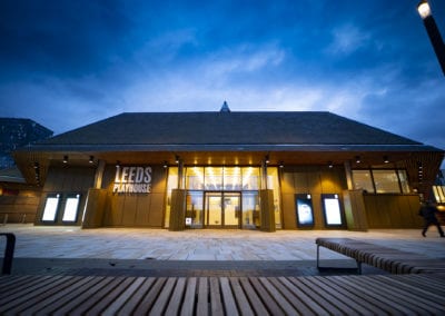 Leeds Playhouse, a renowned performing arts venue in Leeds, UK, featuring a striking facade with wood accents and glass.