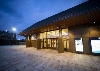 Leeds Playhouse theater exterior at night, with warm lighting and modern architecture.