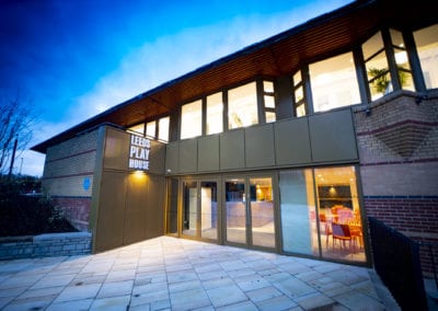 The inviting glow of Leeds Playhouse welcomes theatergoers under a twilight sky.
